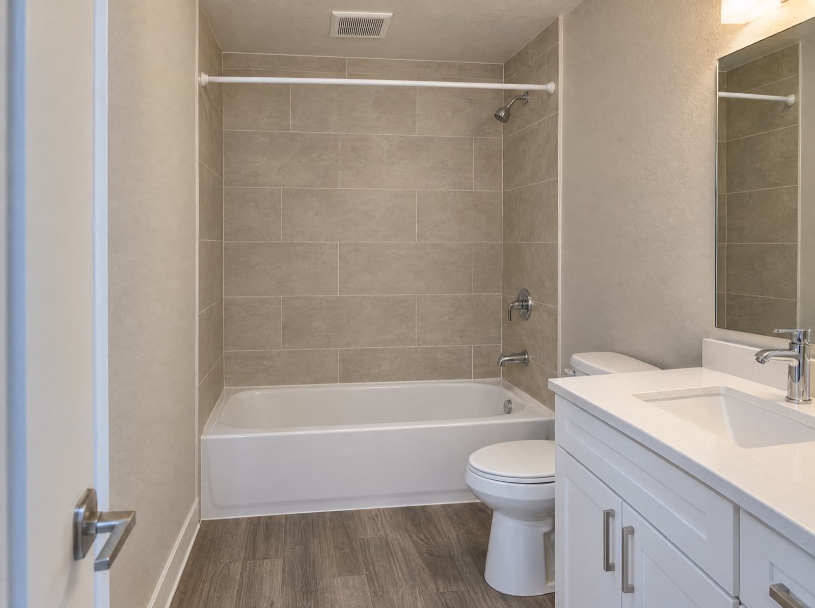 Apartment bathroom with a tiled tub surround, vanity and fixtures