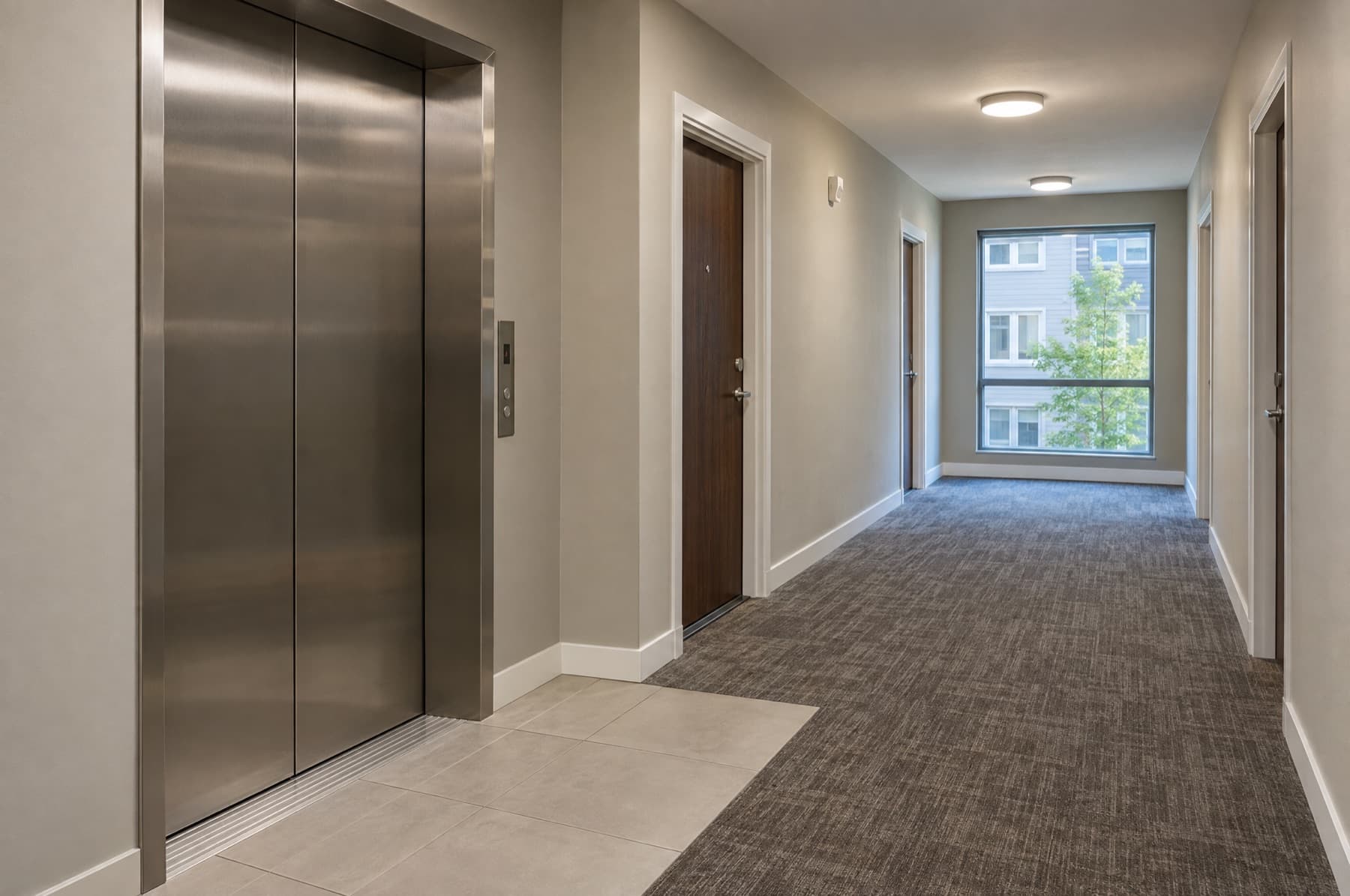 Apartment corridor with an elevator landing and carpeted hallway