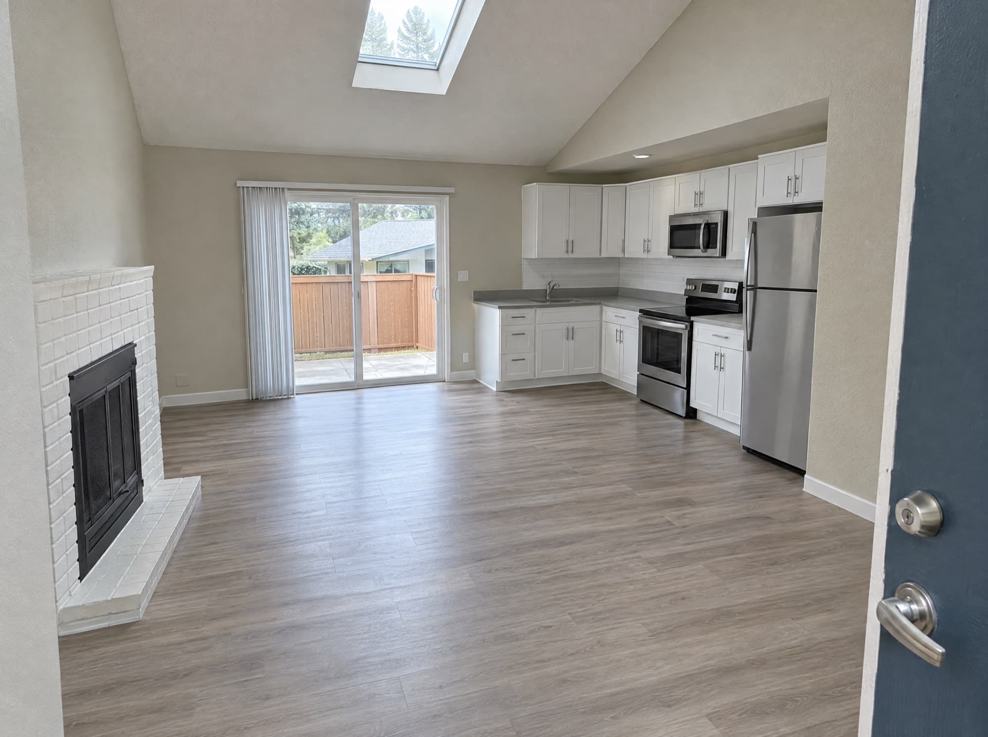 Vacant apartment with a fireplace, plank flooring and an open kitchen