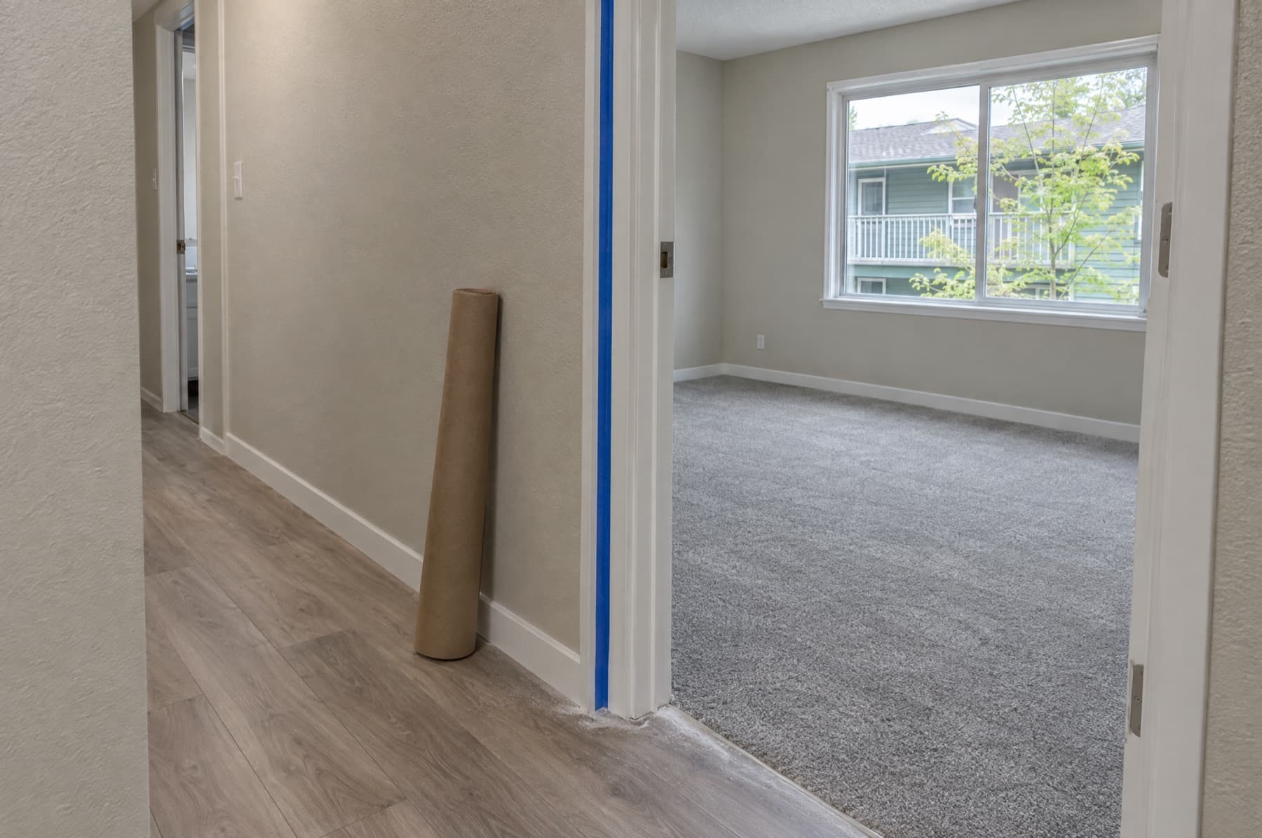 Renovated apartment hallway with plank flooring and painter’s tape on the door casing