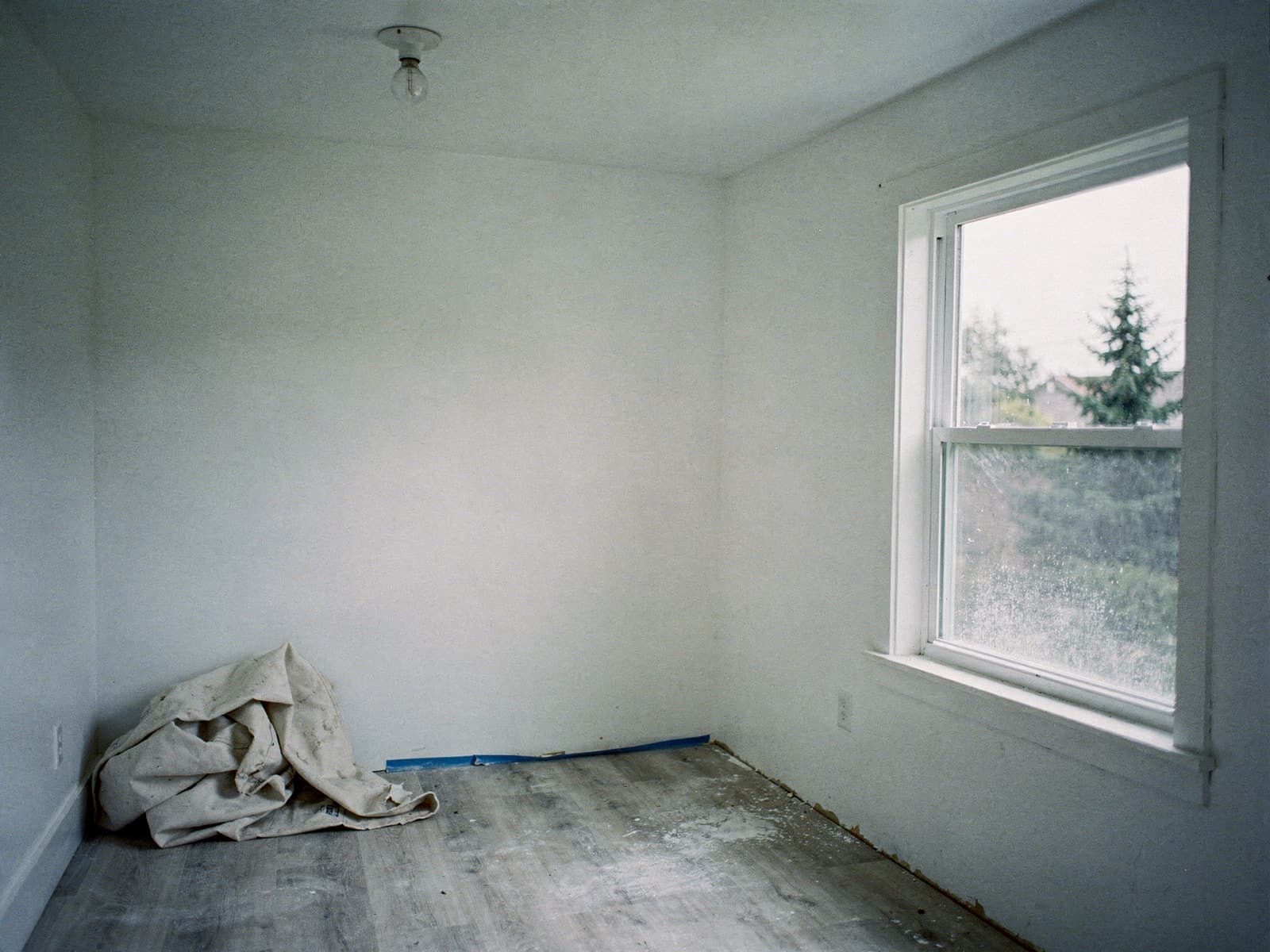 Empty apartment room after renovation with painter tape at the trim and dust on the windowsill